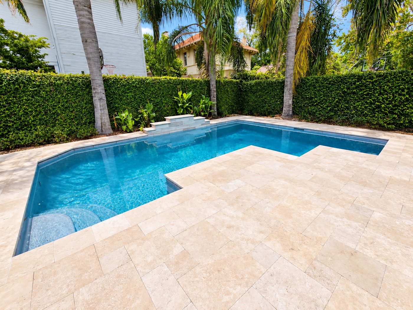 After: the same pool with a new travertine deck and edge
