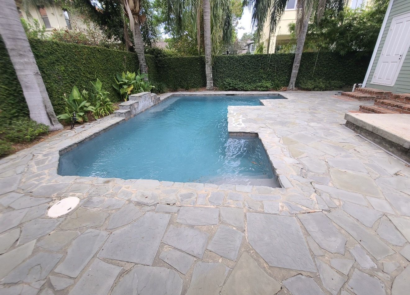 Before: pool surrounded by an uneven gray flagstone deck