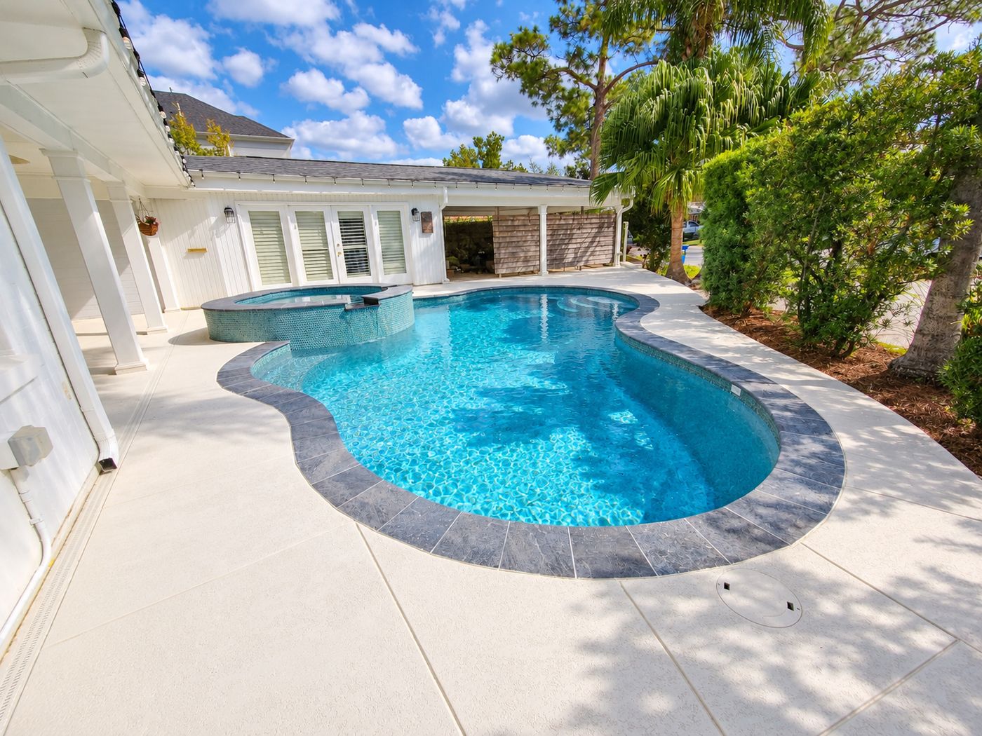 Freeform pool with attached spa and coated concrete deck